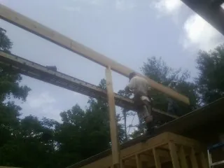 Carpenter setting a ridge beam over a new addition frame — Ice Dam Removal by Roofing Brothers in Simpson