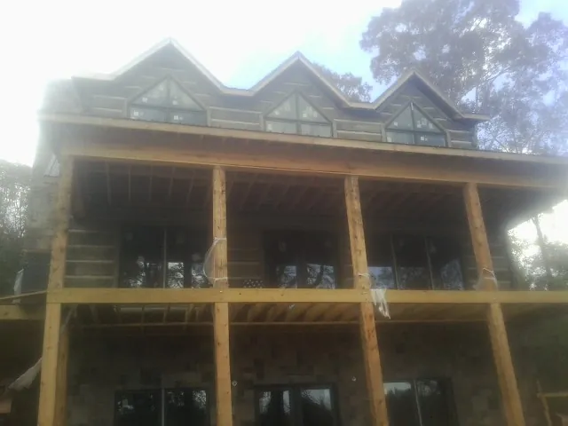 Dormers and porch framing on a large log home under construction — Roof Coating work by our crew in Simpson