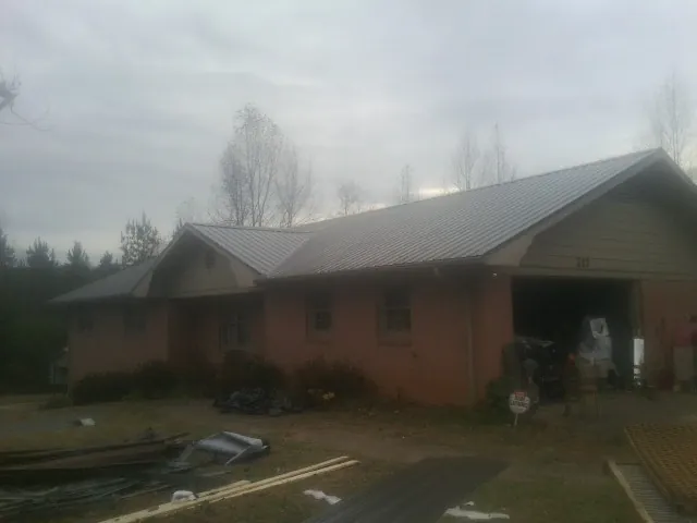 Gray metal roof on a stucco house with an attached garage in Simpson