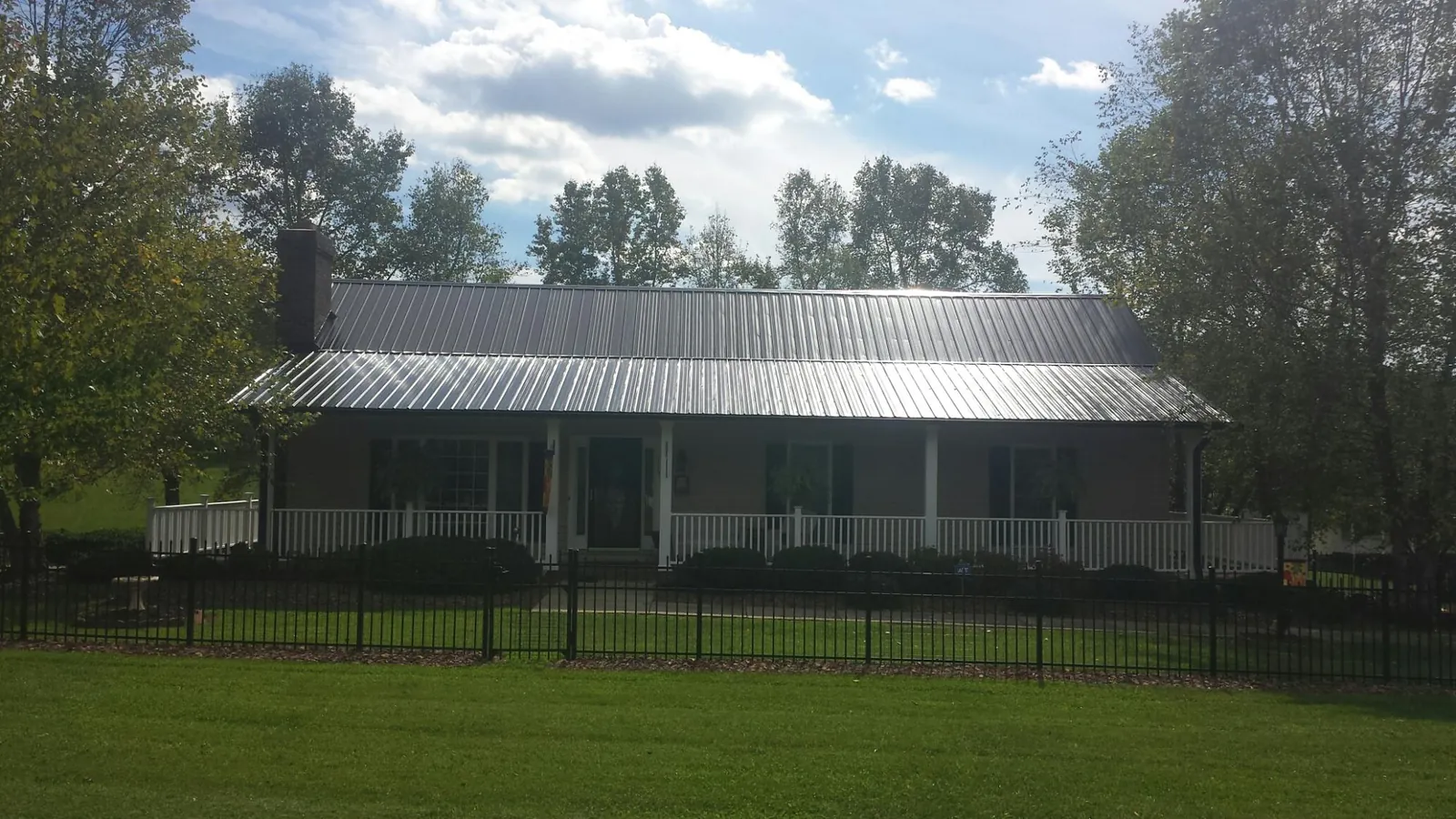 Gray metal roof on a brick ranch with a full width front porch — Gutter Guard Installation work by our crew in Simpson